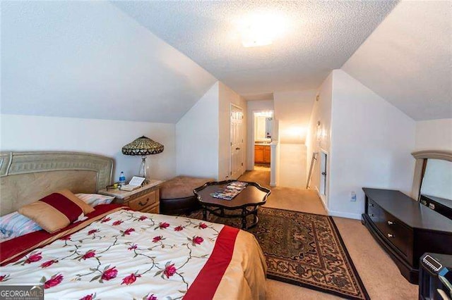 bedroom with ensuite bath, lofted ceiling, light colored carpet, and a textured ceiling