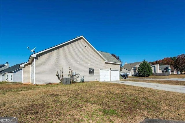 view of side of home featuring a yard, central AC unit, and a garage