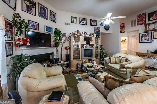 living room featuring ceiling fan and a fireplace