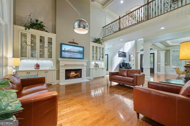 living room with light hardwood / wood-style flooring, a towering ceiling, and beamed ceiling