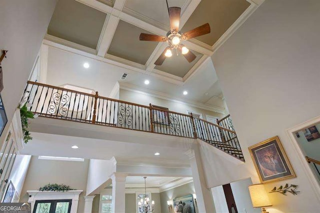 stairs featuring decorative columns, a towering ceiling, coffered ceiling, and ornamental molding