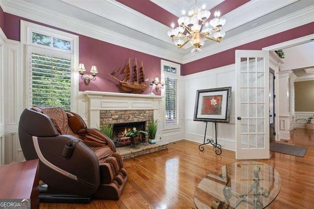 sitting room featuring a fireplace, wood-type flooring, an inviting chandelier, and ornamental molding