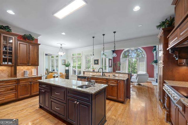 kitchen featuring a center island with sink, sink, hanging light fixtures, and a wealth of natural light