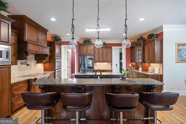 kitchen featuring a kitchen bar, dark stone counters, light wood-type flooring, and appliances with stainless steel finishes