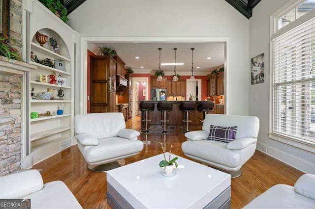 living room with crown molding, built in features, dark wood-type flooring, and a towering ceiling