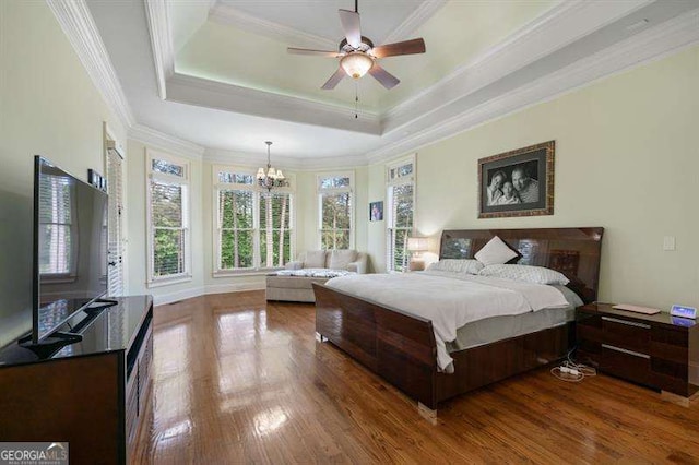 bedroom featuring a raised ceiling, ornamental molding, ceiling fan with notable chandelier, and hardwood / wood-style flooring