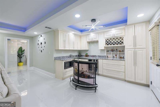 kitchen featuring a raised ceiling, stainless steel microwave, and beverage cooler