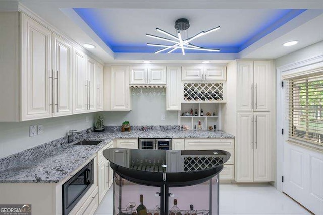 kitchen with a raised ceiling, black microwave, and white cabinets