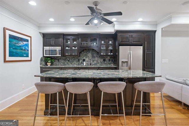 bar featuring backsplash, crown molding, light hardwood / wood-style flooring, stone countertops, and stainless steel appliances