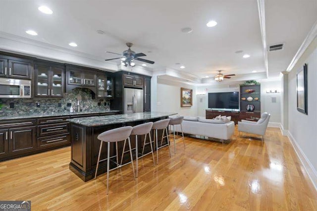 kitchen featuring a center island, light hardwood / wood-style flooring, tasteful backsplash, a kitchen bar, and stainless steel appliances