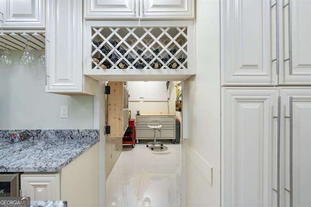 kitchen featuring light stone counters and white cabinetry