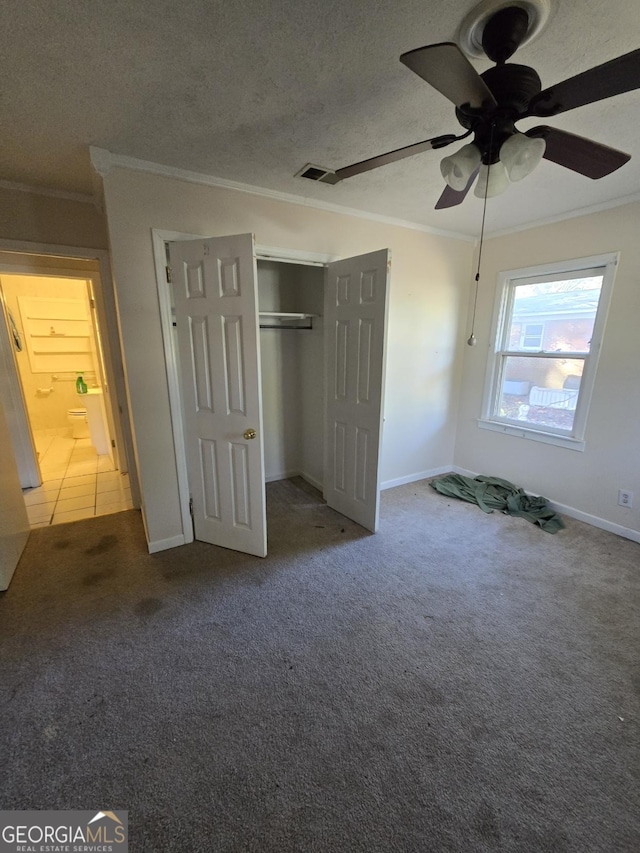 unfurnished bedroom featuring carpet, ceiling fan, ornamental molding, a textured ceiling, and a closet