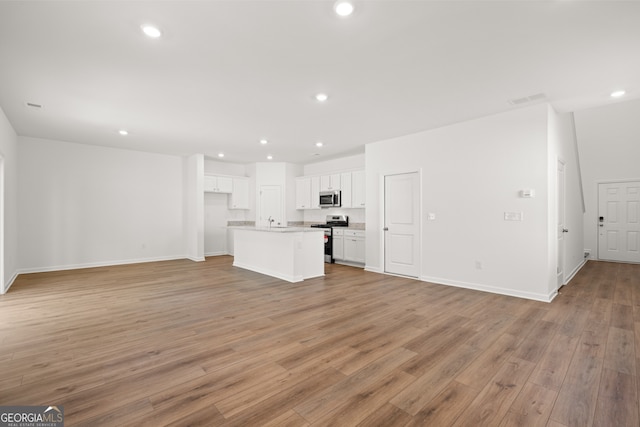 unfurnished living room with sink and light hardwood / wood-style flooring