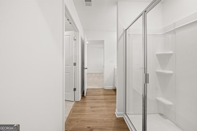 bathroom with a shower with door, vanity, and wood-type flooring