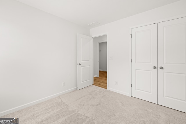 unfurnished bedroom featuring light carpet and a closet