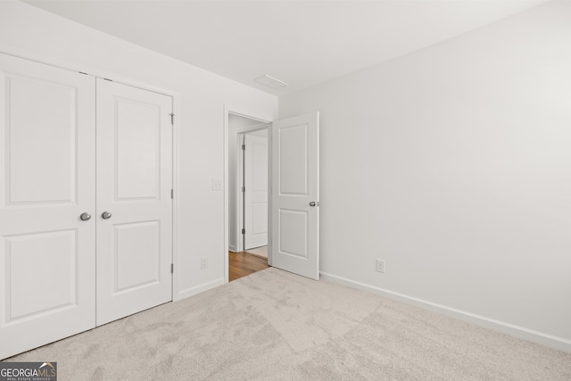 unfurnished bedroom featuring light carpet and a closet