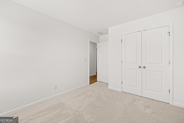 unfurnished bedroom featuring light carpet and a closet