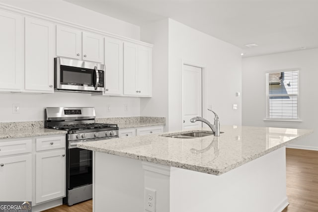 kitchen featuring appliances with stainless steel finishes, a center island with sink, and white cabinetry