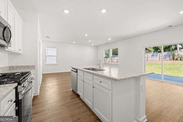 kitchen with white cabinets, sink, stainless steel appliances, and light hardwood / wood-style flooring