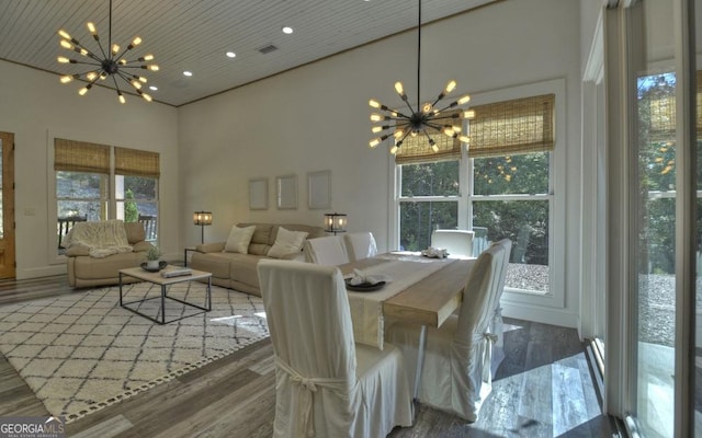 dining area featuring dark hardwood / wood-style flooring, a towering ceiling, and a chandelier