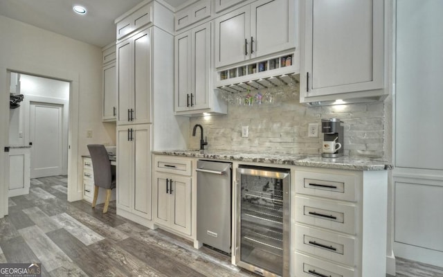 kitchen featuring white cabinets, hardwood / wood-style flooring, light stone counters, and beverage cooler