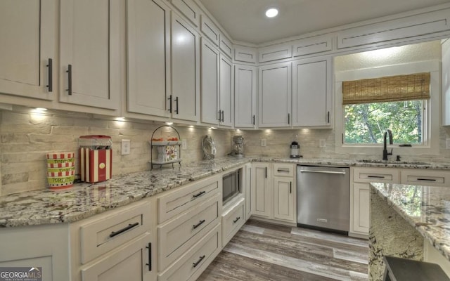 kitchen featuring decorative backsplash, appliances with stainless steel finishes, light stone countertops, sink, and light hardwood / wood-style floors