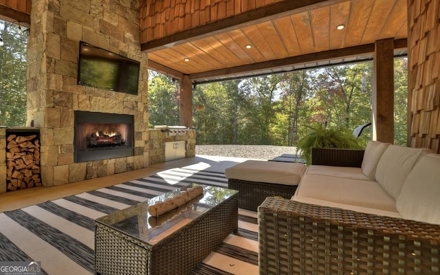 sunroom featuring a wealth of natural light, wood ceiling, and an outdoor stone fireplace