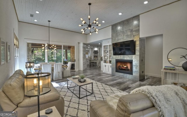 living room with a towering ceiling, a fireplace, dark wood-type flooring, wooden ceiling, and a chandelier