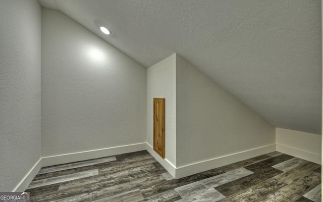 bonus room with a textured ceiling, dark hardwood / wood-style floors, and lofted ceiling