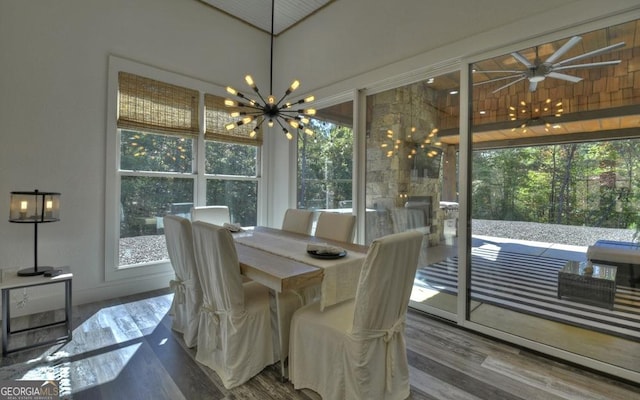 dining space featuring ceiling fan with notable chandelier and wood-type flooring