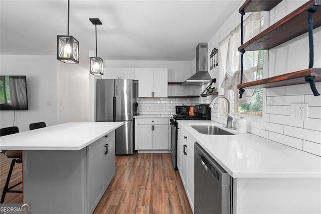 kitchen featuring white cabinets, stainless steel appliances, wall chimney exhaust hood, and sink