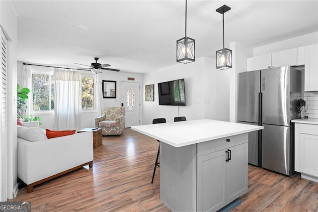 kitchen featuring a center island, white cabinetry, stainless steel refrigerator, and dark wood-type flooring