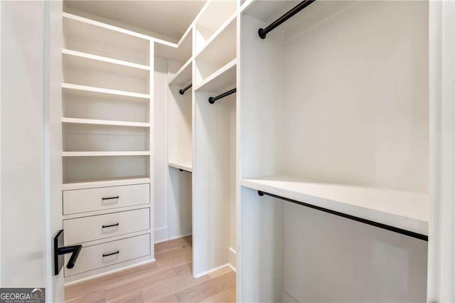 walk in closet with light hardwood / wood-style flooring