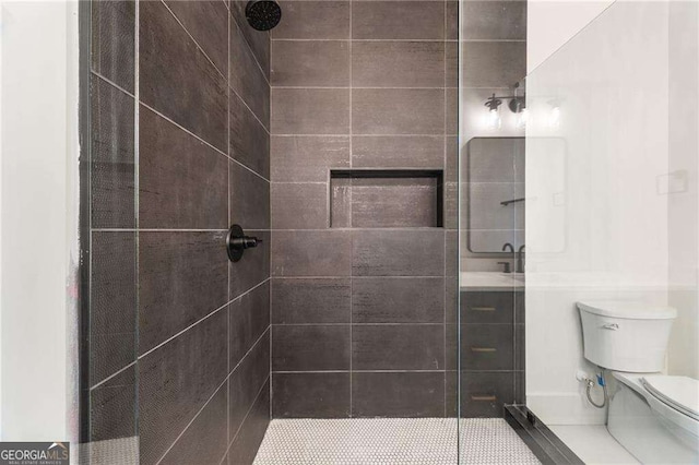 bathroom featuring tiled shower and toilet