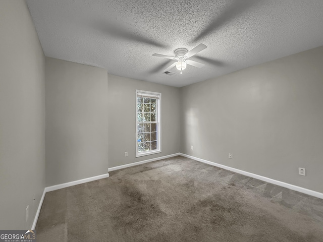 spare room featuring a textured ceiling, dark carpet, and ceiling fan