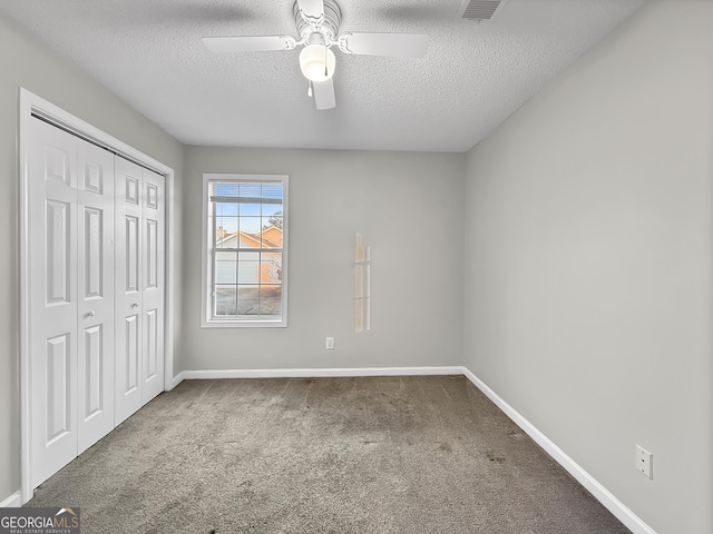 unfurnished bedroom featuring carpet, ceiling fan, a textured ceiling, and a closet