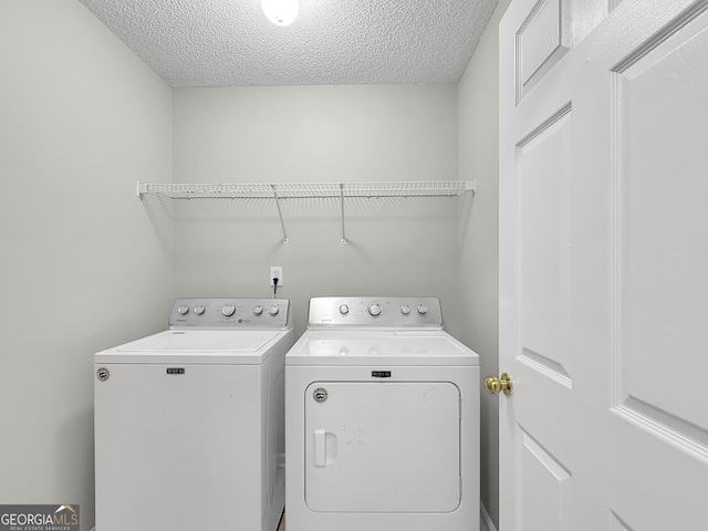 laundry area with separate washer and dryer and a textured ceiling