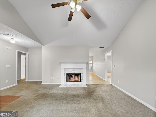 unfurnished living room featuring ceiling fan, a premium fireplace, a textured ceiling, lofted ceiling, and light carpet