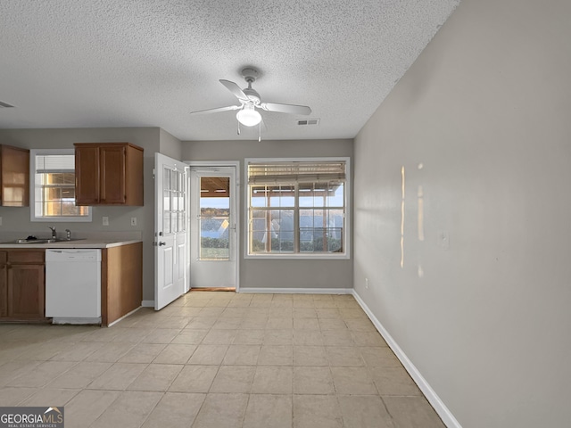 kitchen featuring dishwasher, sink, ceiling fan, light tile patterned floors, and a textured ceiling