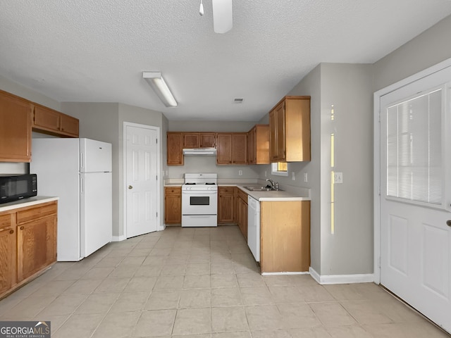 kitchen featuring a textured ceiling, white appliances, light tile patterned floors, and sink