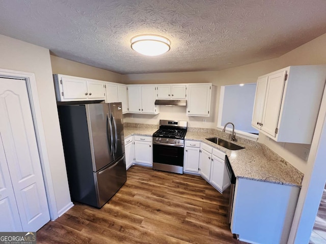 kitchen with light stone countertops, white cabinetry, sink, stainless steel appliances, and dark hardwood / wood-style flooring