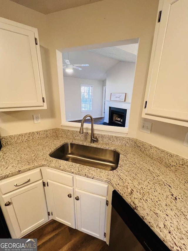 kitchen with dark wood-type flooring, white cabinets, sink, stainless steel dishwasher, and ceiling fan