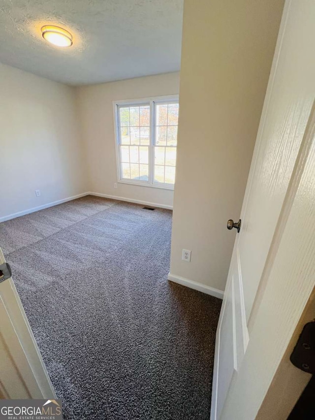 carpeted empty room featuring a textured ceiling