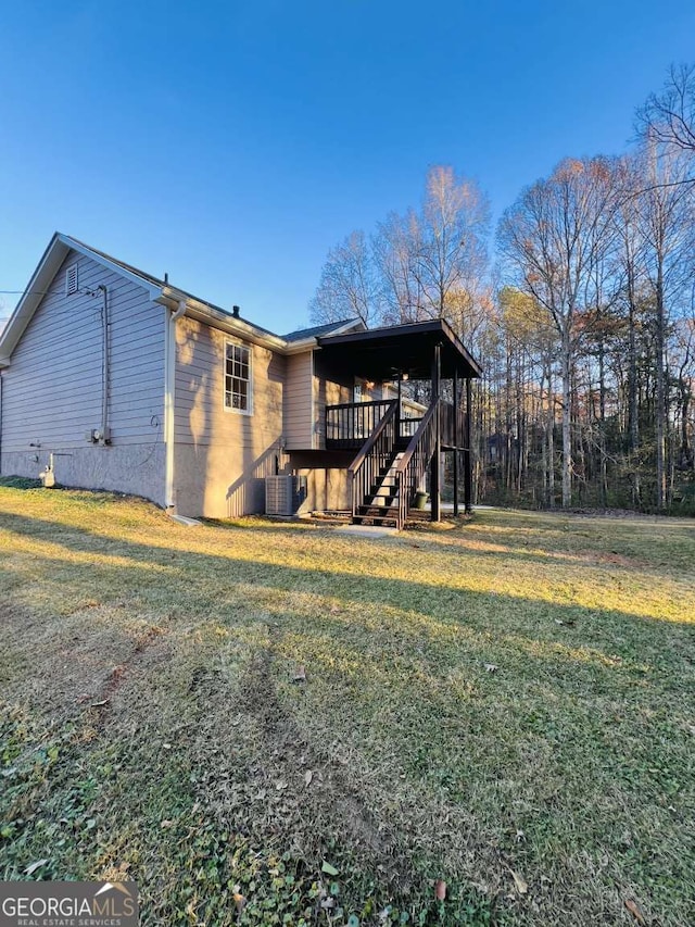 rear view of property featuring cooling unit, a wooden deck, and a lawn