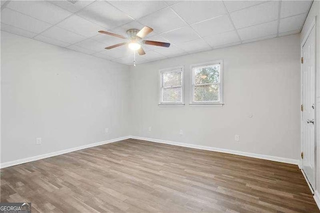 spare room featuring ceiling fan, hardwood / wood-style floors, and a drop ceiling