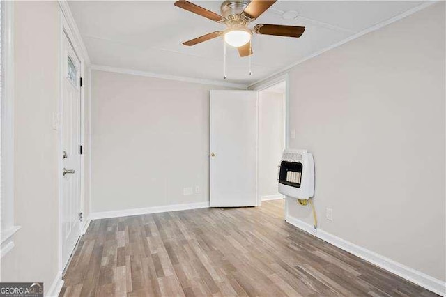 empty room with heating unit, crown molding, light hardwood / wood-style flooring, and ceiling fan