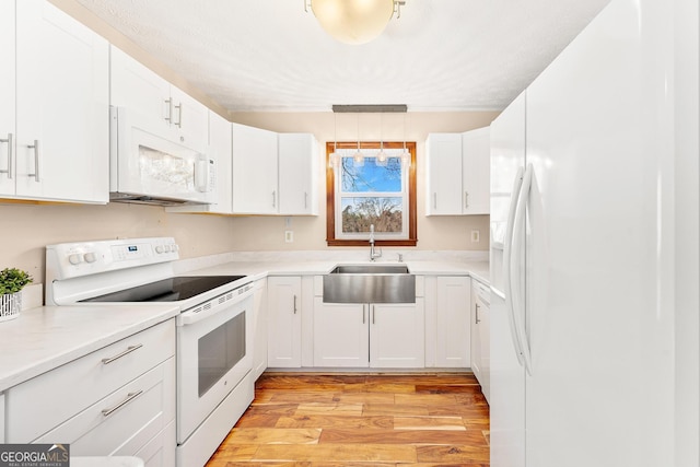 kitchen with white appliances, white cabinetry, and sink