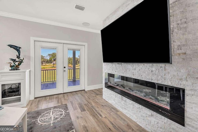 unfurnished living room featuring a fireplace, french doors, light hardwood / wood-style flooring, and crown molding