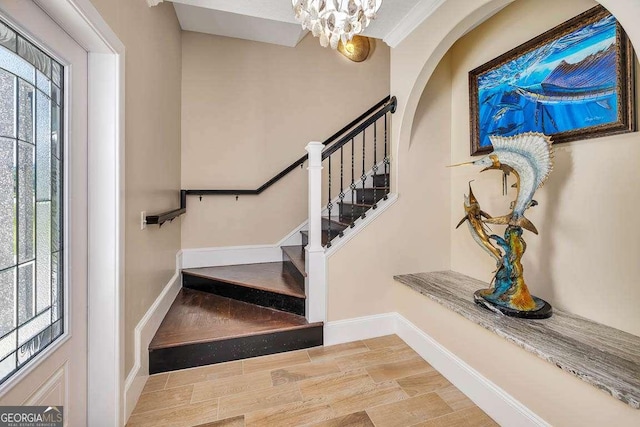 foyer entrance featuring plenty of natural light, ornamental molding, a chandelier, and light hardwood / wood-style flooring