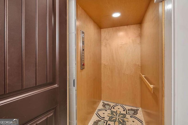 interior space featuring elevator and wood walls